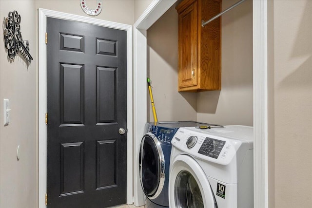 clothes washing area featuring cabinet space and washer and dryer