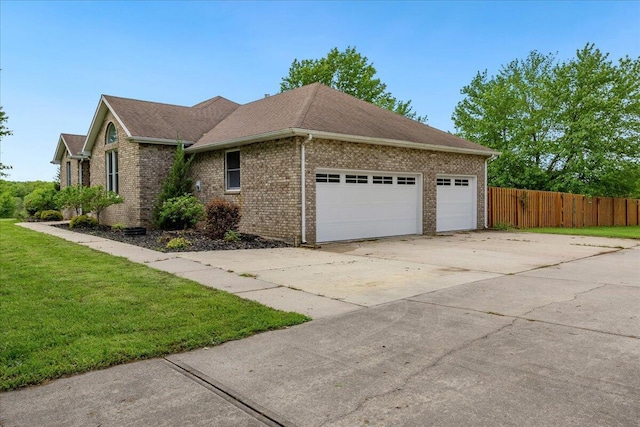 view of home's exterior with a garage, fence, driveway, brick siding, and a yard