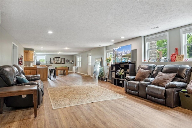living area featuring light wood-style floors, recessed lighting, a textured ceiling, and visible vents