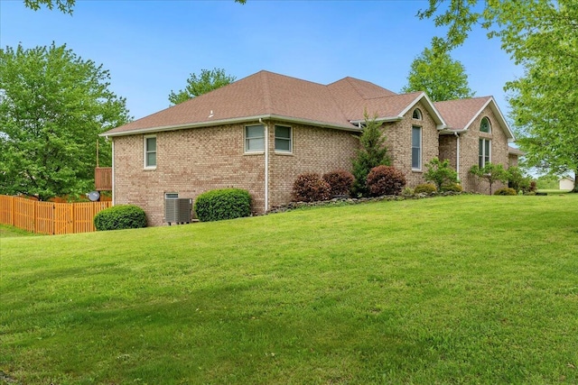 view of front of home with fence, a front yard, central AC, and brick siding