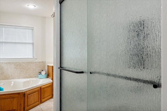 bathroom featuring tile patterned flooring, a stall shower, and a bath