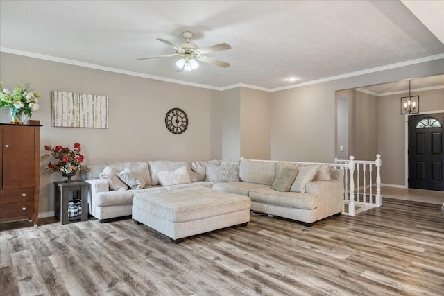 living room with crown molding, baseboards, wood finished floors, and ceiling fan with notable chandelier