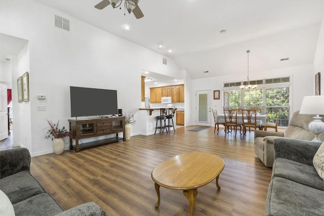 living room featuring high vaulted ceiling, ceiling fan with notable chandelier, baseboards, wood finished floors, and visible vents
