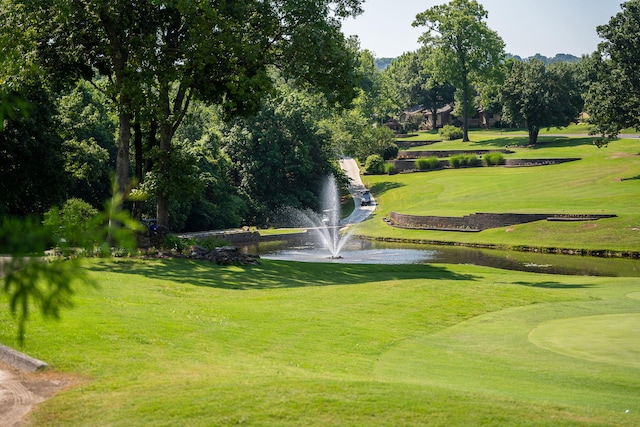 view of community with a lawn, a water view, and view of golf course