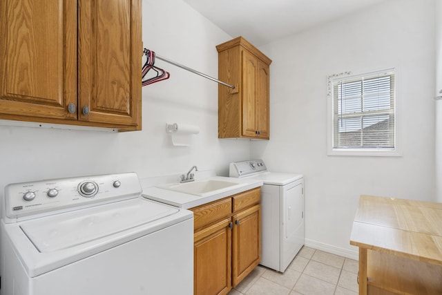 laundry room featuring washing machine and clothes dryer, light tile patterned flooring, cabinet space, a sink, and baseboards