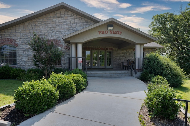 doorway to property featuring a porch, french doors, and stone siding