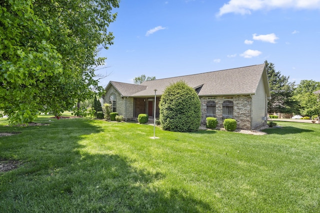 view of front of house featuring a shingled roof, a front lawn, and brick siding