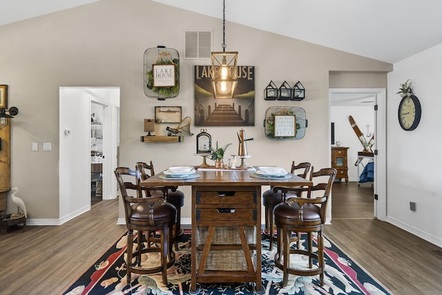dining room featuring baseboards, vaulted ceiling, wood finished floors, and visible vents