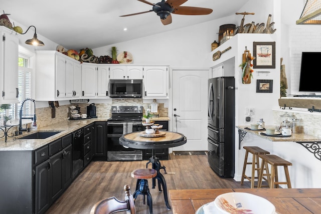 kitchen with ceiling fan, vaulted ceiling, a sink, black appliances, and white cabinetry