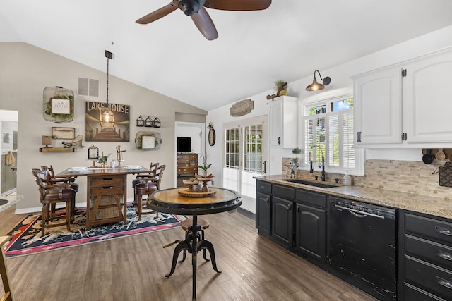 kitchen featuring white cabinets, a sink, visible vents, dishwasher, and vaulted ceiling
