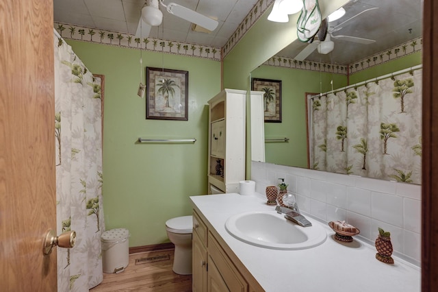 3623 Ridge Dr, Joplin, MO 64801 - bathroom featuring vanity, decorative backsplash, wood finished floors, toilet, and a ceiling fan