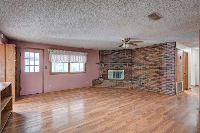 3623 Ridge Dr, Joplin, MO 64801 - unfurnished living room with visible vents, wood finished floors, brick wall, ceiling fan, and a textured ceiling
