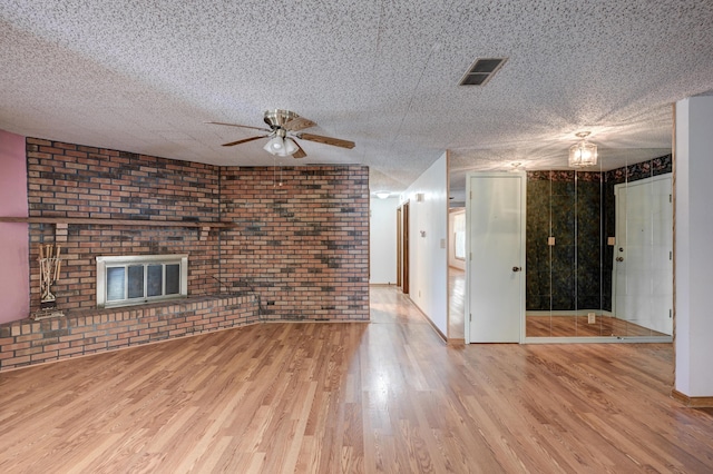 3623 Ridge Dr, Joplin, MO 64801 - unfurnished living room featuring ceiling fan, brick wall, visible vents, a fireplace, and wood finished floors