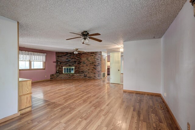 3623 Ridge Dr, Joplin, MO 64801 - unfurnished living room featuring a ceiling fan, a textured ceiling, a fireplace, baseboards, and light wood-style flooring
