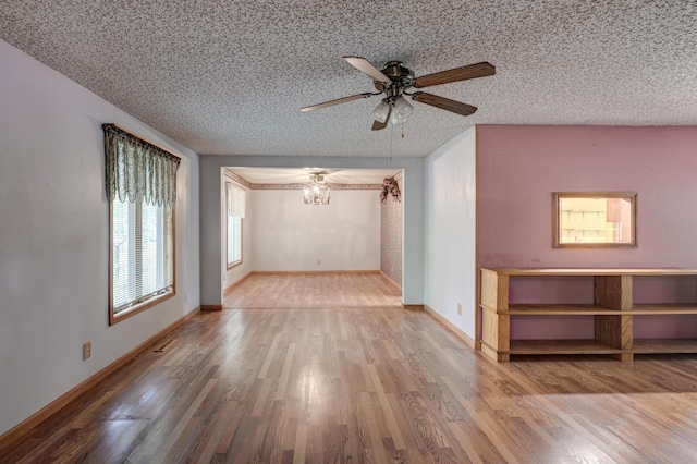 3623 Ridge Dr, Joplin, MO 64801 - unfurnished living room with baseboards, a textured ceiling, ceiling fan with notable chandelier, and wood finished floors