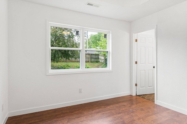 unfurnished room with visible vents, baseboards, and dark wood-style floors