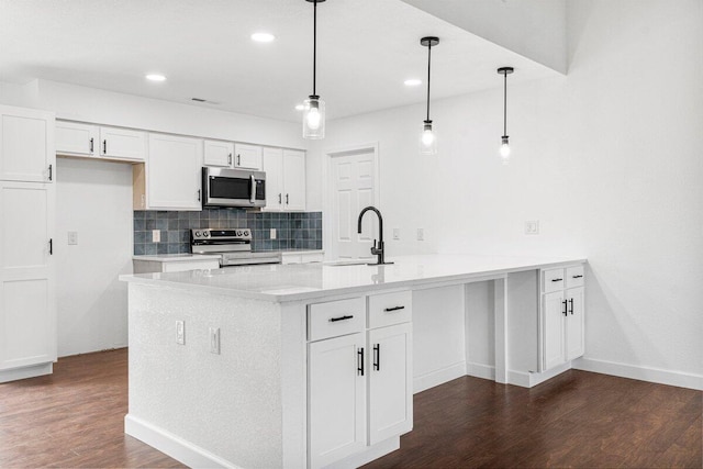 kitchen featuring decorative backsplash, appliances with stainless steel finishes, a sink, white cabinets, and a peninsula