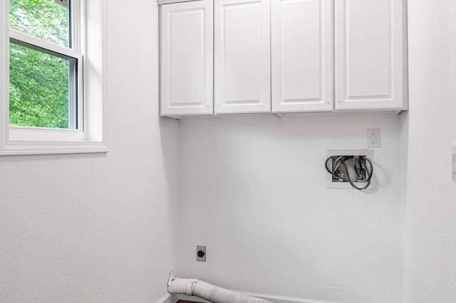 clothes washing area with cabinet space, hookup for an electric dryer, and baseboards