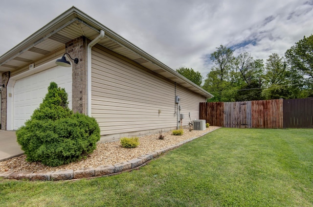 view of side of property featuring a lawn, a garage, fence, and brick siding