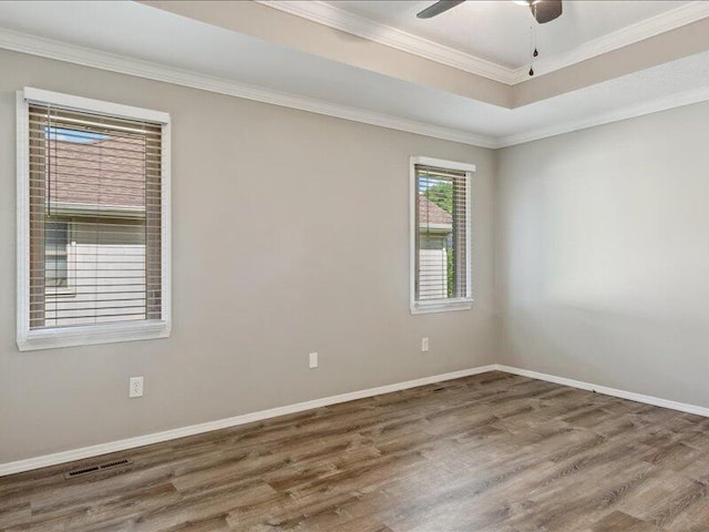 spare room featuring visible vents, crown molding, wood finished floors, baseboards, and a ceiling fan