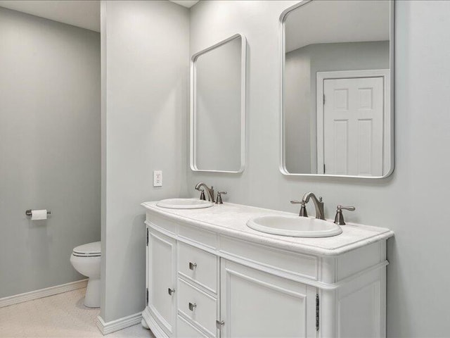 full bath featuring a sink, baseboards, toilet, and double vanity