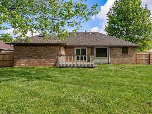 rear view of house featuring a lawn, brick siding, and fence