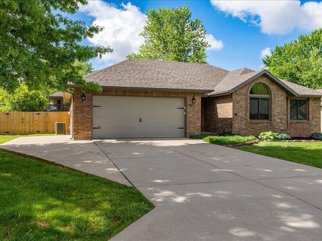 ranch-style home featuring fence, a shingled roof, brick siding, a garage, and concrete driveway