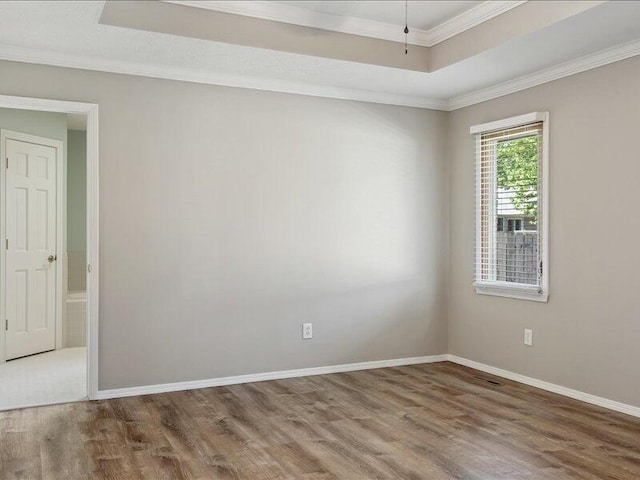 spare room featuring crown molding, a raised ceiling, and wood finished floors