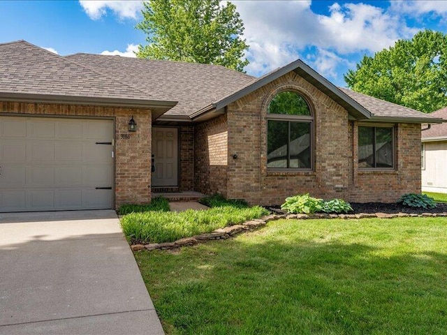 ranch-style home featuring roof with shingles, an attached garage, a front yard, and brick siding
