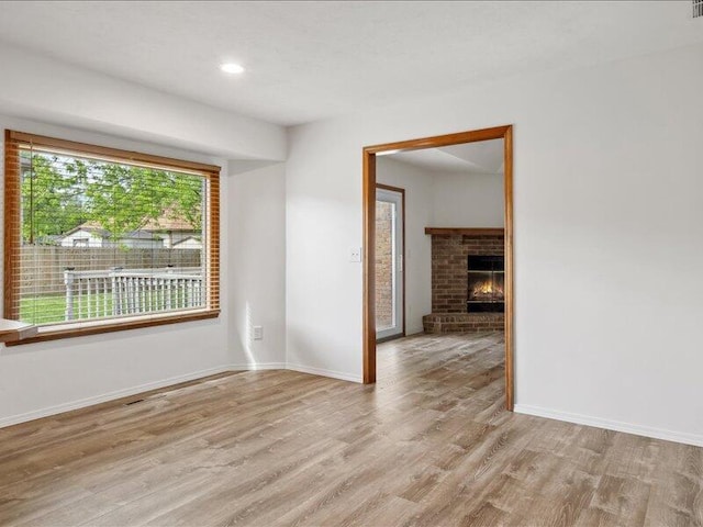 unfurnished room featuring light wood-style floors, baseboards, and a fireplace
