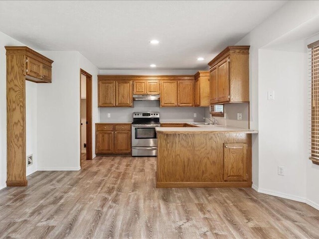 kitchen with under cabinet range hood, stainless steel range with electric cooktop, brown cabinets, and light wood-style floors