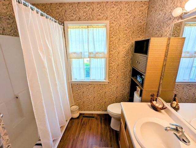 bathroom with vanity, toilet, wallpapered walls, and wood finished floors