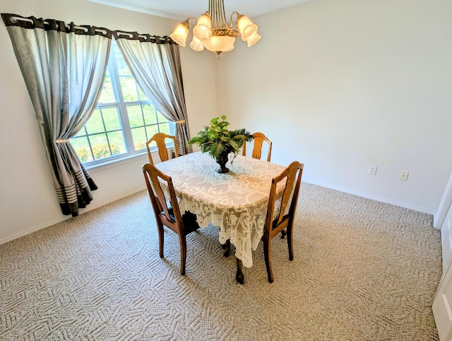 dining area featuring an inviting chandelier, baseboards, and light colored carpet