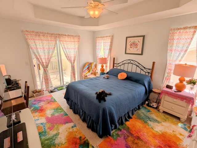 carpeted bedroom featuring ceiling fan and a raised ceiling