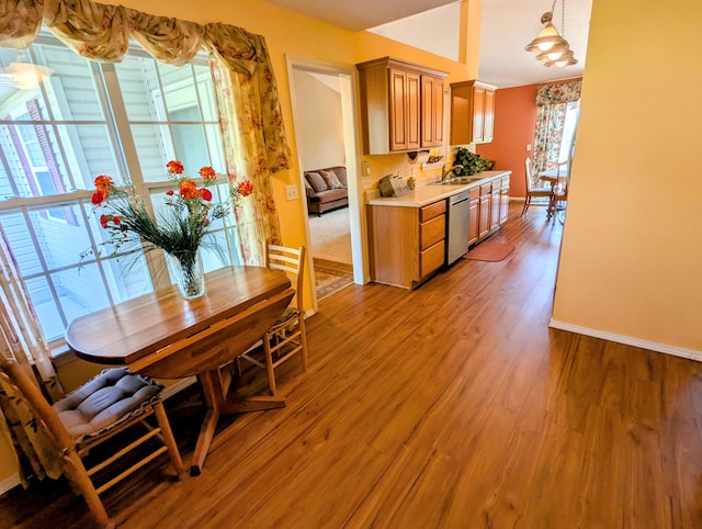 kitchen featuring a sink, light wood-style floors, light countertops, baseboards, and stainless steel dishwasher