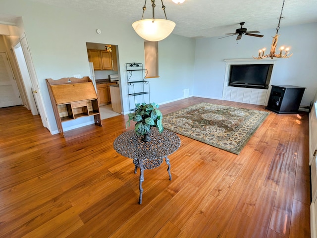 living room featuring baseboards, ceiling fan with notable chandelier, and light wood-style floors