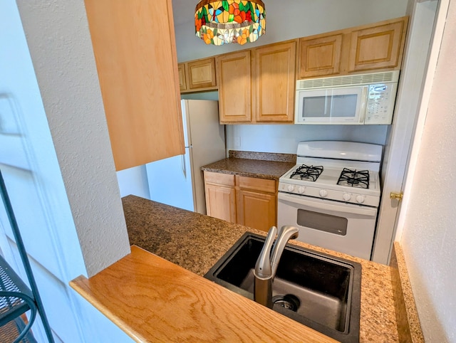 kitchen with white appliances, light brown cabinetry, and a sink