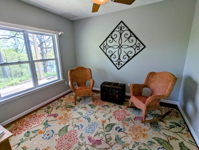 living area with a ceiling fan and baseboards