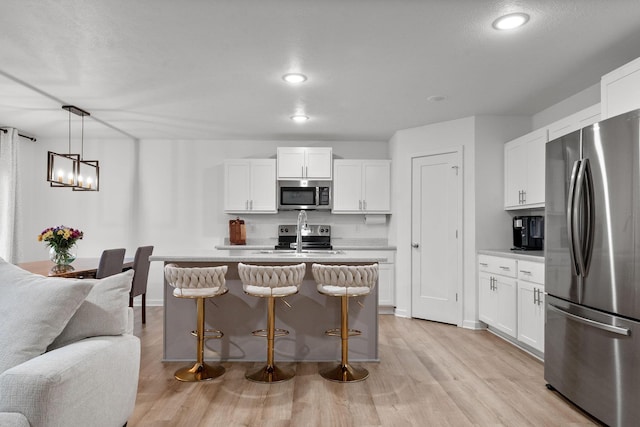 kitchen with a sink, light wood-style flooring, appliances with stainless steel finishes, and light countertops