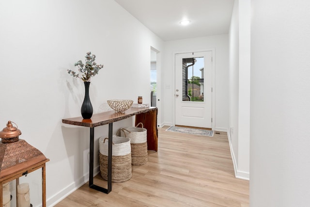 doorway featuring baseboards and light wood finished floors