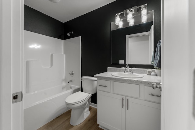 bathroom featuring vanity, toilet, baseboards, wood finished floors, and  shower combination