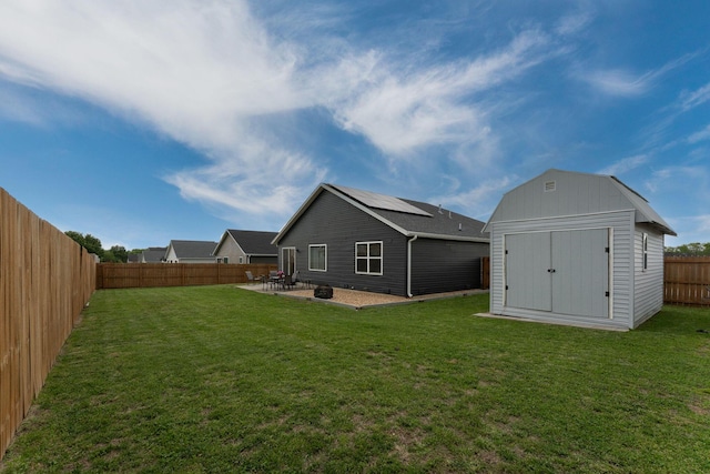 rear view of property featuring a storage shed, a patio, a lawn, and a fenced backyard