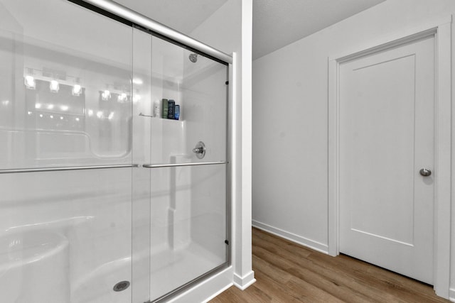 full bath with baseboards, a stall shower, and wood finished floors