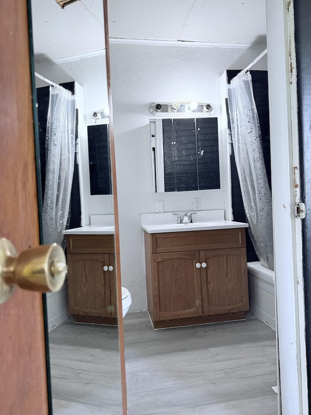 bathroom featuring vanity, shower / bath combo with shower curtain, toilet, and wood finished floors