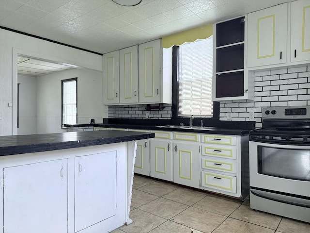 kitchen with backsplash, electric range, dark countertops, a sink, and white cabinets