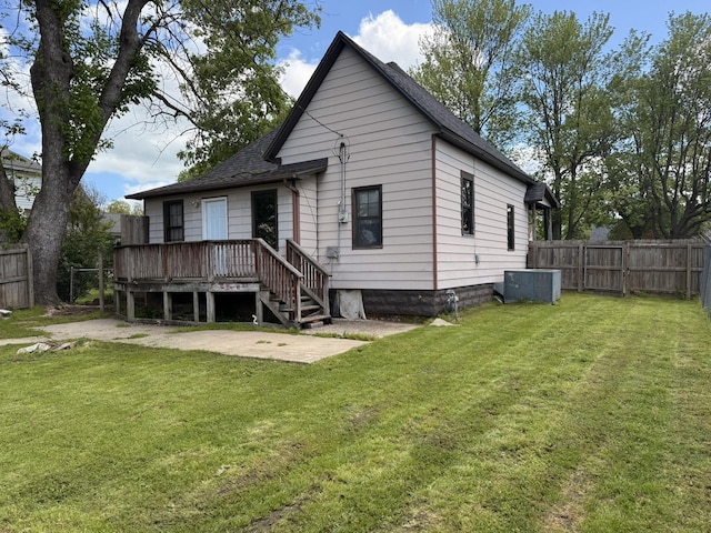 back of house with a fenced backyard, a wooden deck, a shingled roof, and a lawn