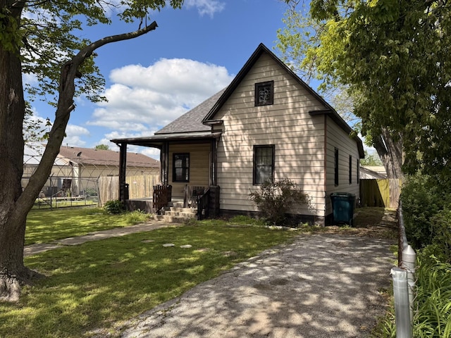 view of front of property featuring roof with shingles, fence, and a front yard