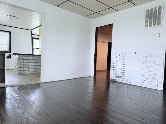 unfurnished room featuring wood-type flooring, visible vents, and wainscoting