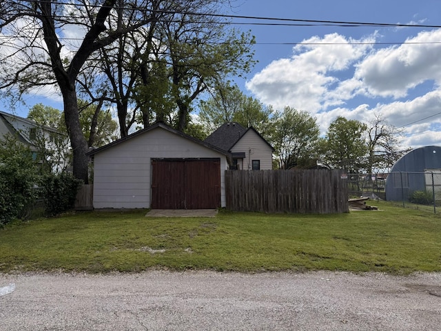 exterior space featuring an attached garage, fence, and an outbuilding
