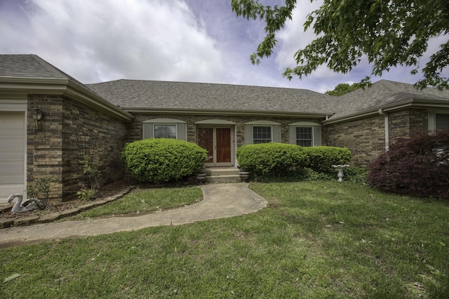 view of front of home featuring an attached garage, a shingled roof, and a front lawn